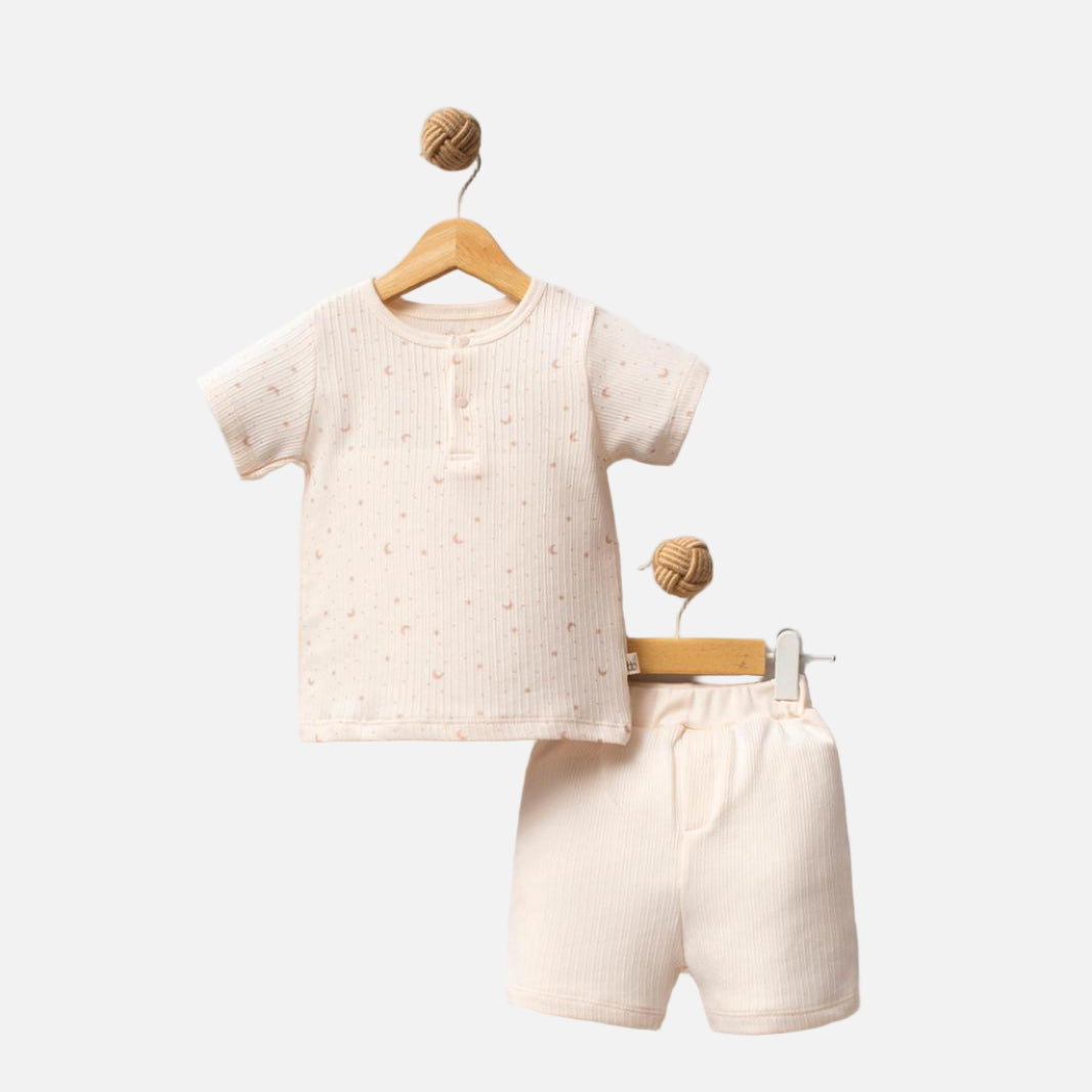 Children's beige outfit with shirt and shorts on hangers against a white background, featuring 'Shiny Moon' brand.