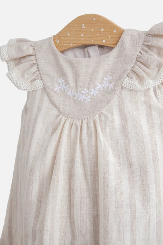 Beige baby dress with floral embroidery on a wooden hanger against a light background