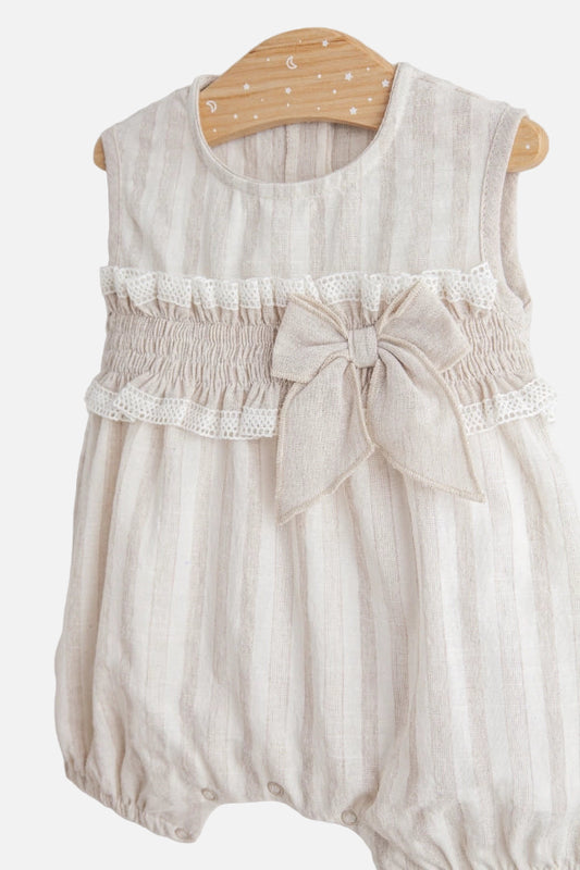 Baby romper with lace details and a bow on a hanger against a white background