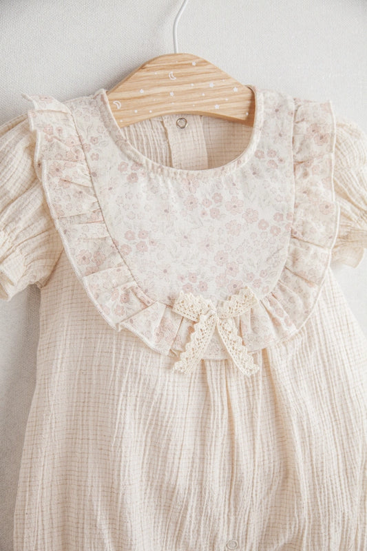 Beige baby dress with lace details on a wooden hanger against a white background