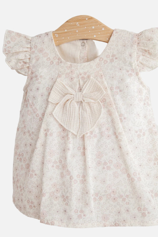 Baby dress with floral pattern and bow on a hanger against a white background