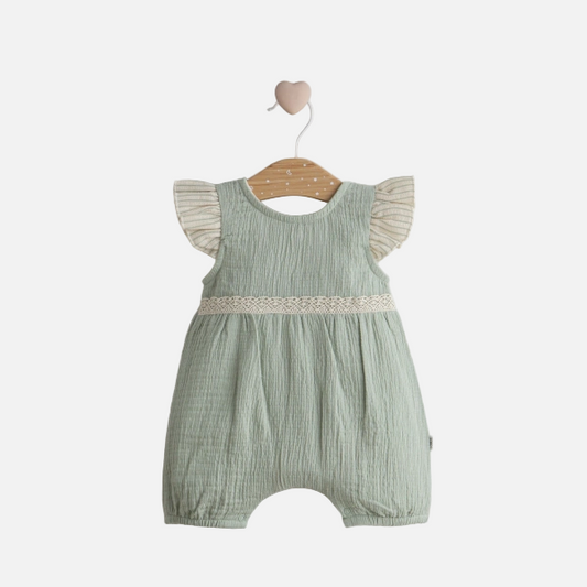Green baby romper with ruffled sleeves on a wooden hanger against a light gray background