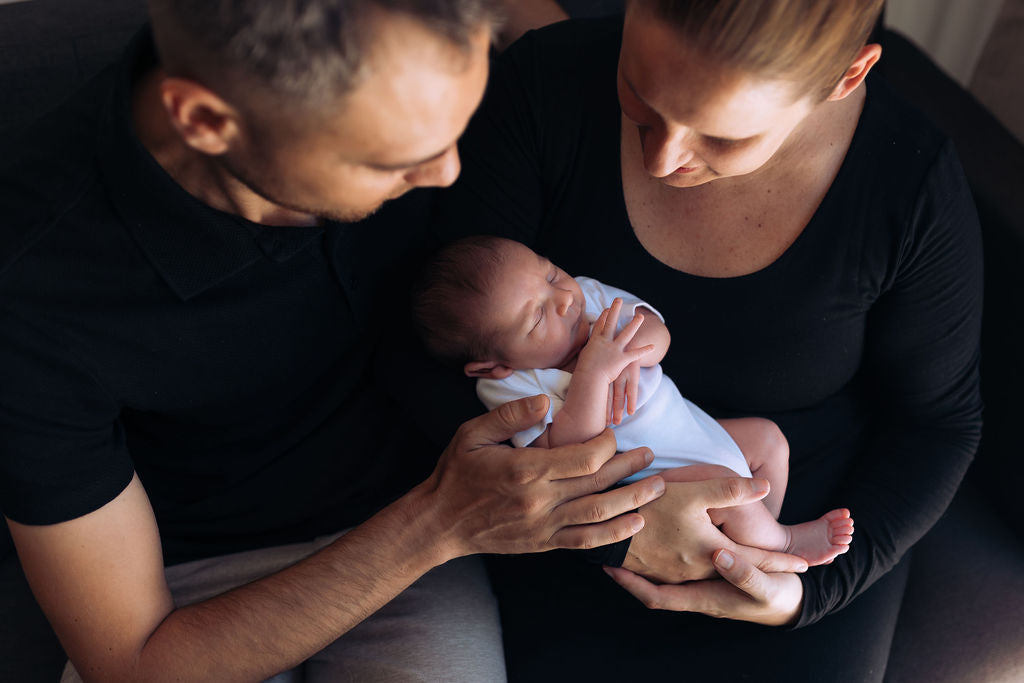 Two adults holding a newborn baby