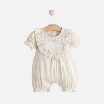 Baby romper with lace details on a hanger against a white background