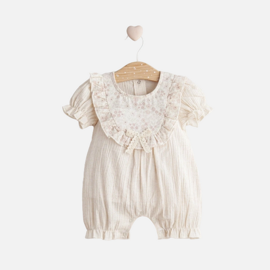 Baby romper with lace details on a hanger against a white background